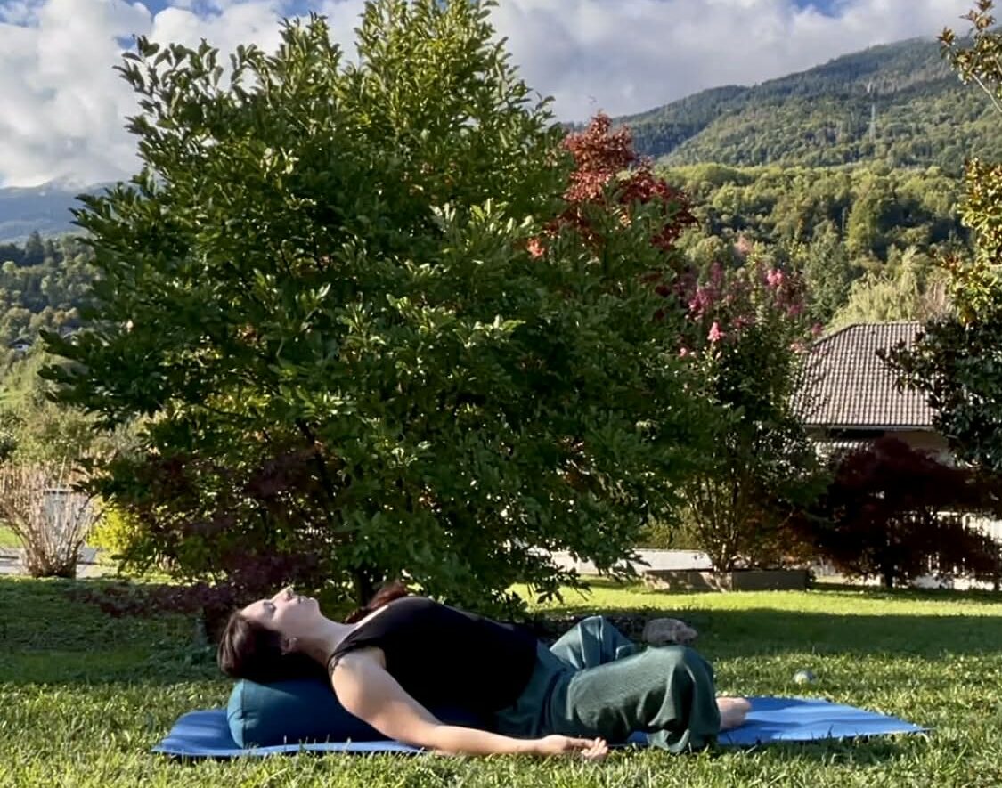 Femme allongée dans l'herbe, en posture du papillon renversé