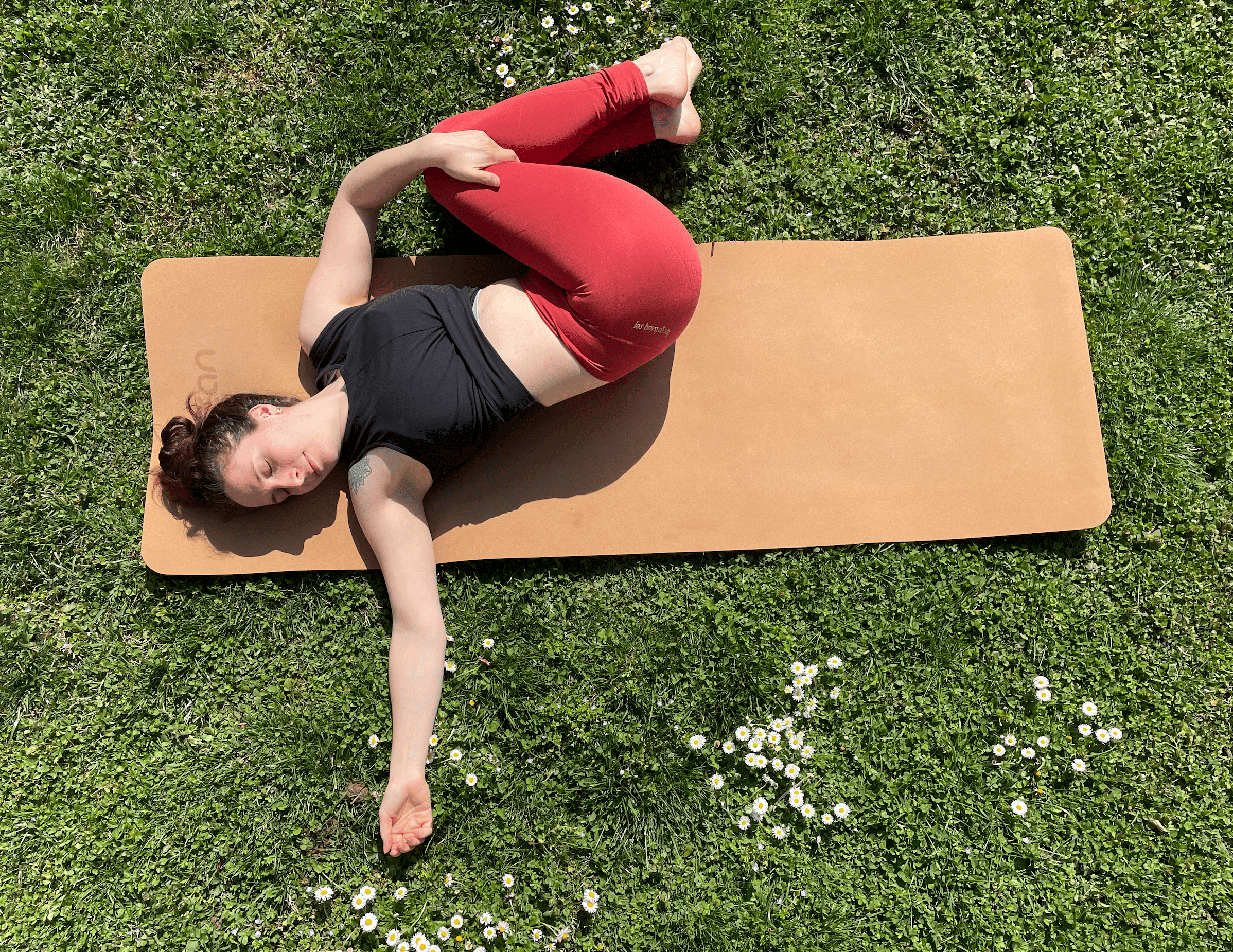 Femme couchée sur un tapis de yoga, en torsion, souriant