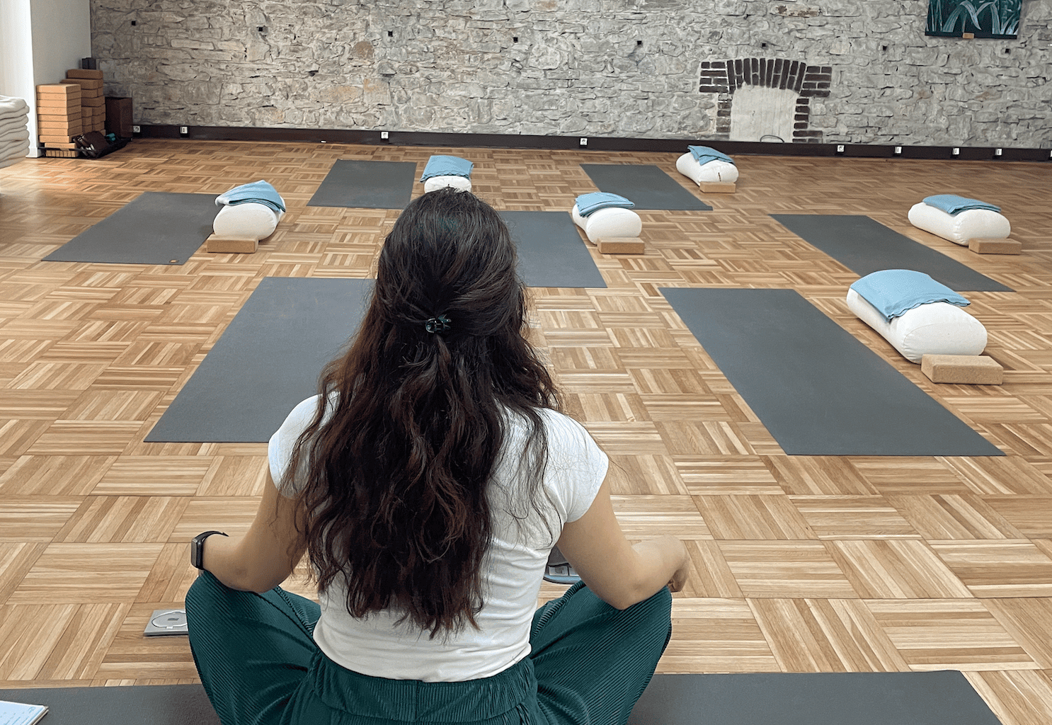 Salle des ateliers naturoyoga : femme de dos, avec face à elle des tapis de yoga installé